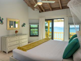 A Dream Come True Villa&rsquo;s master bedroom with a king bed and sliding glass door leading to a private patio over Mahoe Bay.