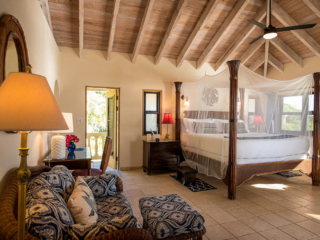 Master Bedroom at A Dream Come True Villa with a four-post king bed, lofted wood-beam ceilings and comfortable sitting area.