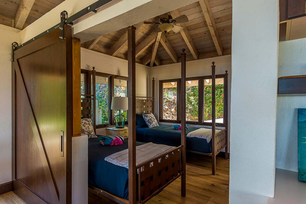Dos Sols Villa’s double bedroom with high ceilings with a fan, two twin beds and large windows providing natural light.