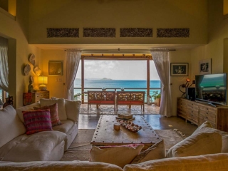 La Vida Villa: Living Room Living room at La Vida Villa with a comfortable wrap-around couch and coffee table and an open door looking out on Nail Bay.