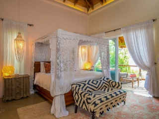 La Vida Villa: Master Bedroom Master bedroom at La Vida Villa with a king-side four-post bed, white curtains and natural light from an open door to a patio.