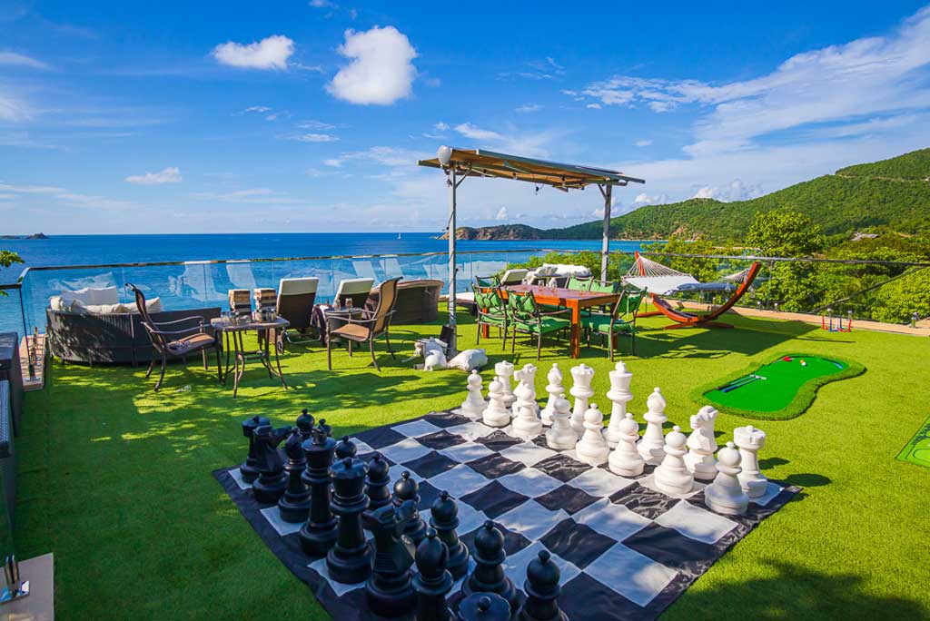 Turf-covered roof deck with a large-scale chess set, putting green with the calm blue sea and sky in the background.