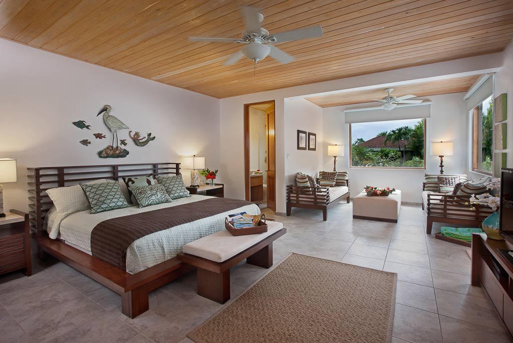 Spacious guest room at Blue Lagoon Villa with a king bed, two twin beds, stone tile flooring and a wood ceiling with a fan.