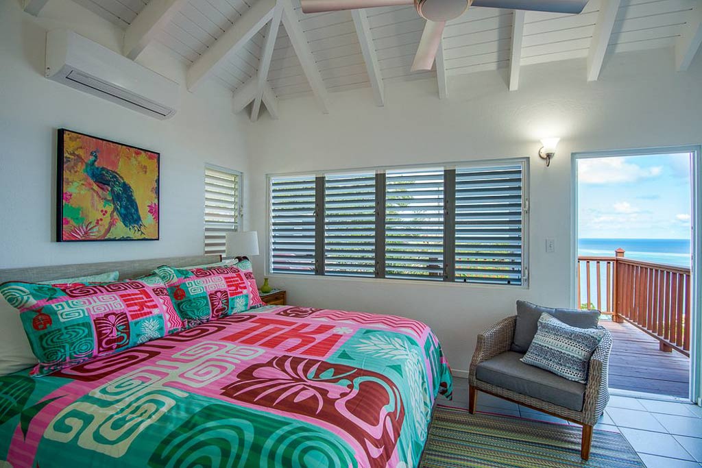 Sea View Villa guest room with a king bed, tropical décor and a door open to a deck overlooking Leverick Bay, Virgin Gorda.
