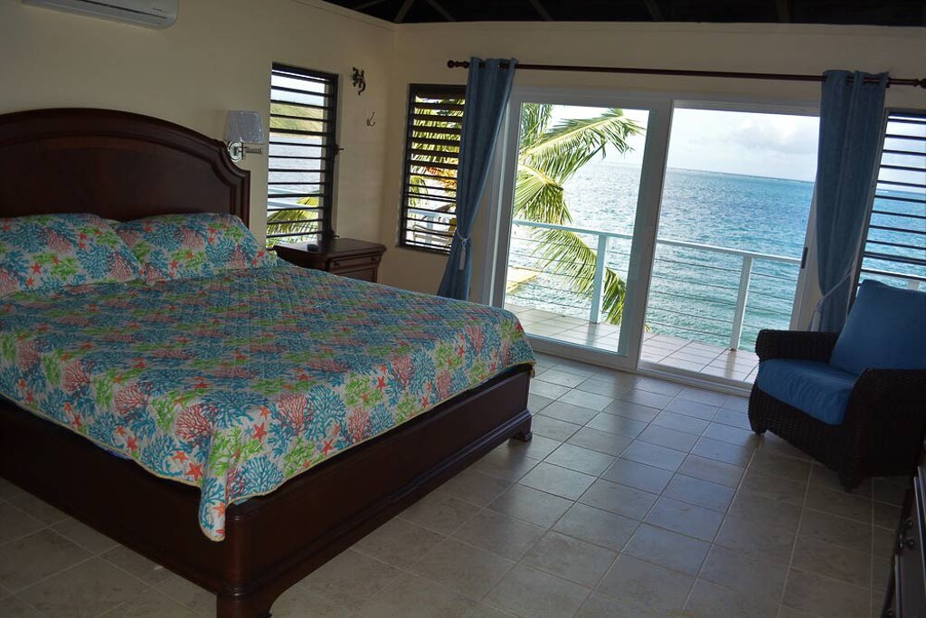 Guest bedroom with king bed and a large glass door leading to the patio overlooking the waters of Leverick Bay.