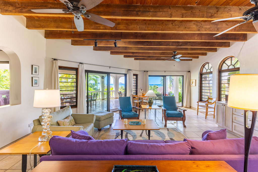 Bright, modern main room at Bellamare Villa with white walls, colorful furnishings and a wood-beam ceiling with ceiling fans.