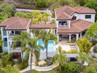 Bellamare Villa: Overhead Bellamare luxury villa with a white stone façade and red tile roof on the tropical hillside at Mahoe Bay, Virgin Gorda.