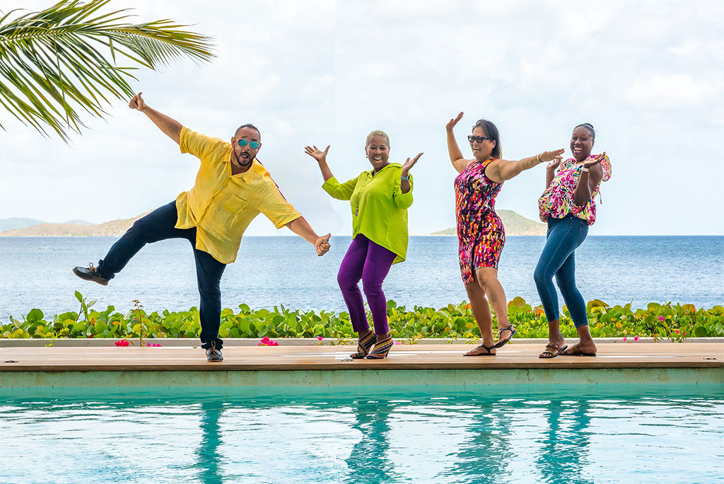 The four members of the VGVR team in colorful clothing poolside with the blue sea and sky in the background.