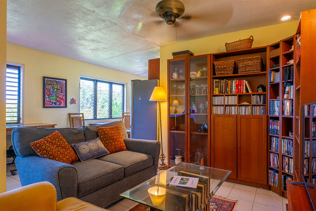 Sitting area with a chair, loveseat and coffee table and a large wooden cabinet with a library of books and games.