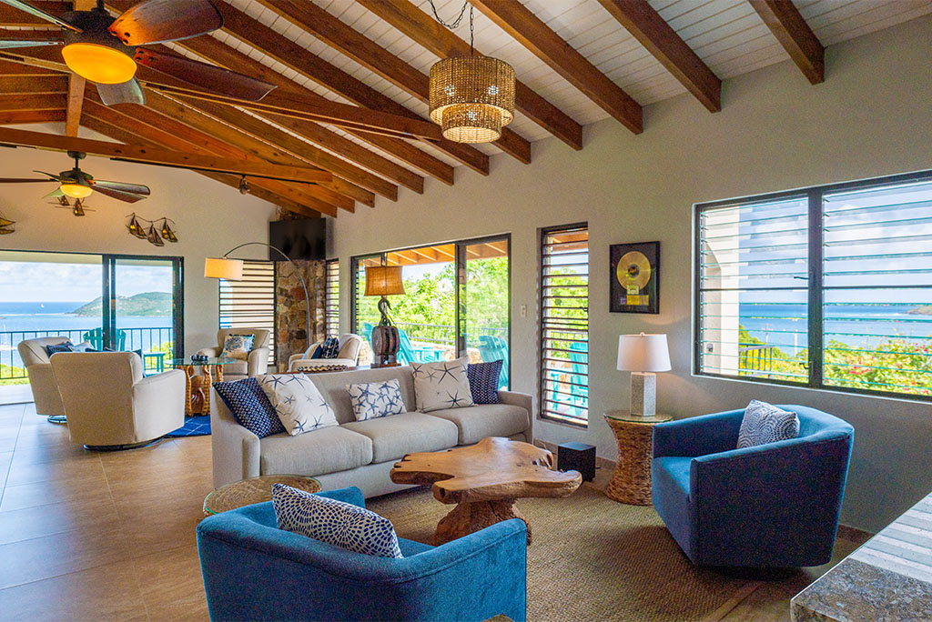 Tamarind Villa’s living area with comfortable cushioned chairs and couch and windows looking out on Leverick Bay.