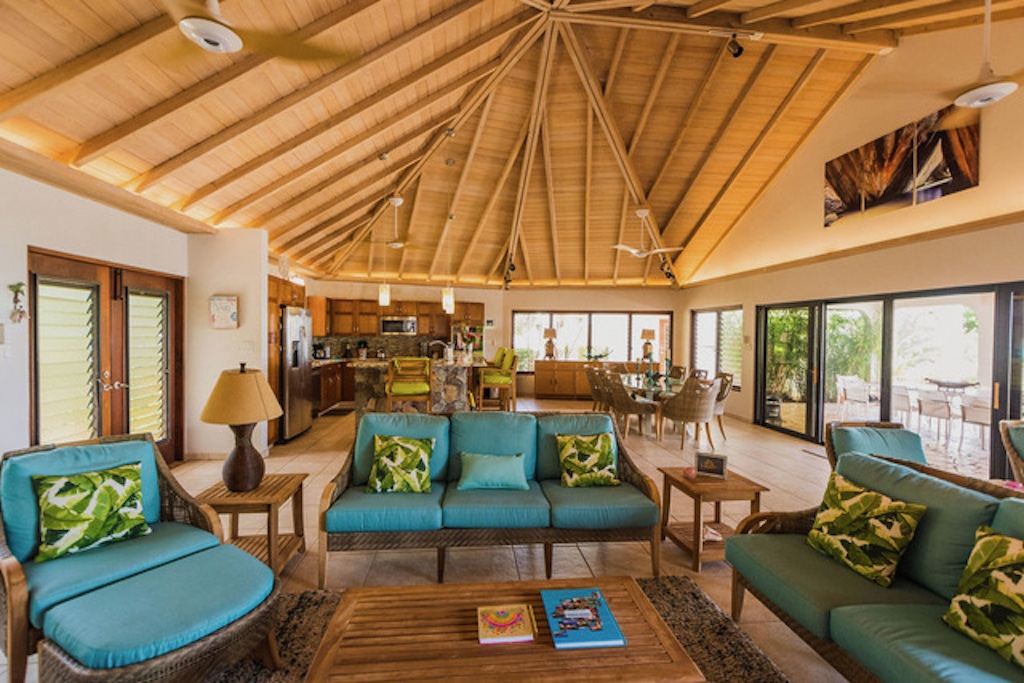 Caribbean Wind Villa’s great room with a conversation seating area with wicker furniture and vaulted ceilings with fans.