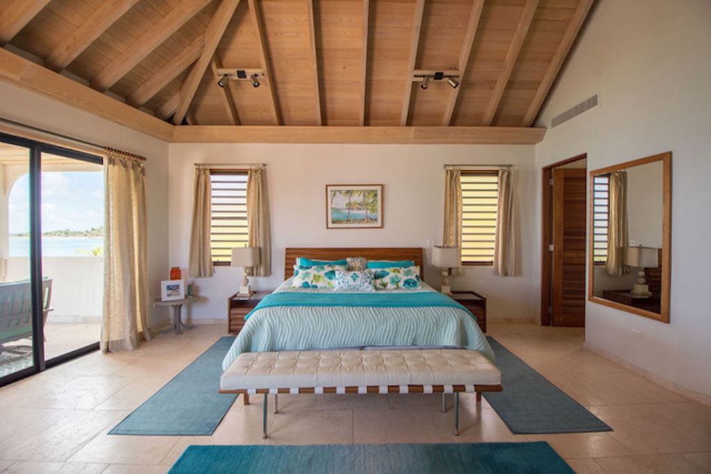 Caribbean Wind second floor master guest room with king bed, stone tile floors and vaulted wood ceilings.