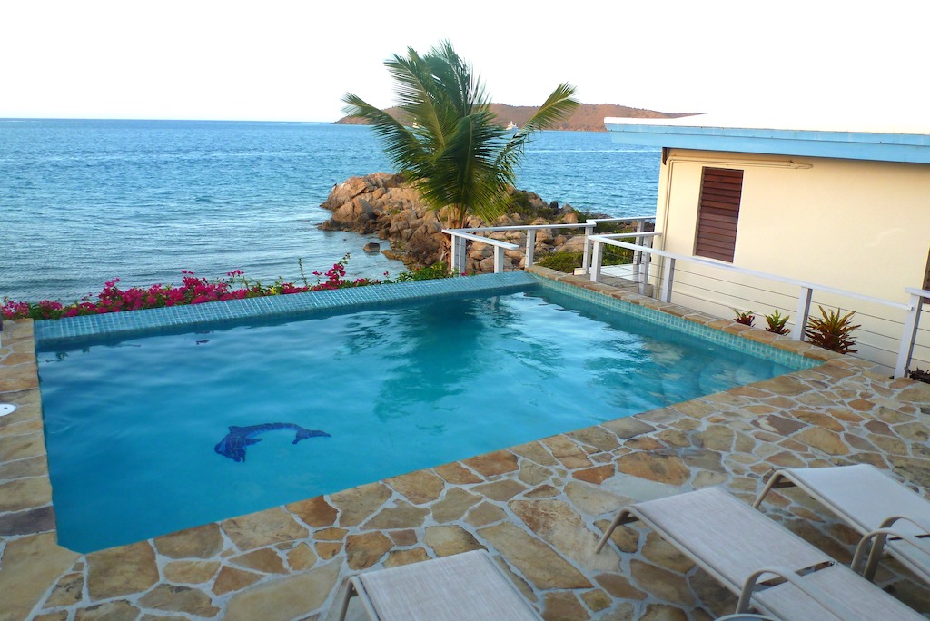 Natural stone patio and swimming pool at Serendipity luxury villa on the waterfront with Leverick Bay in the background.