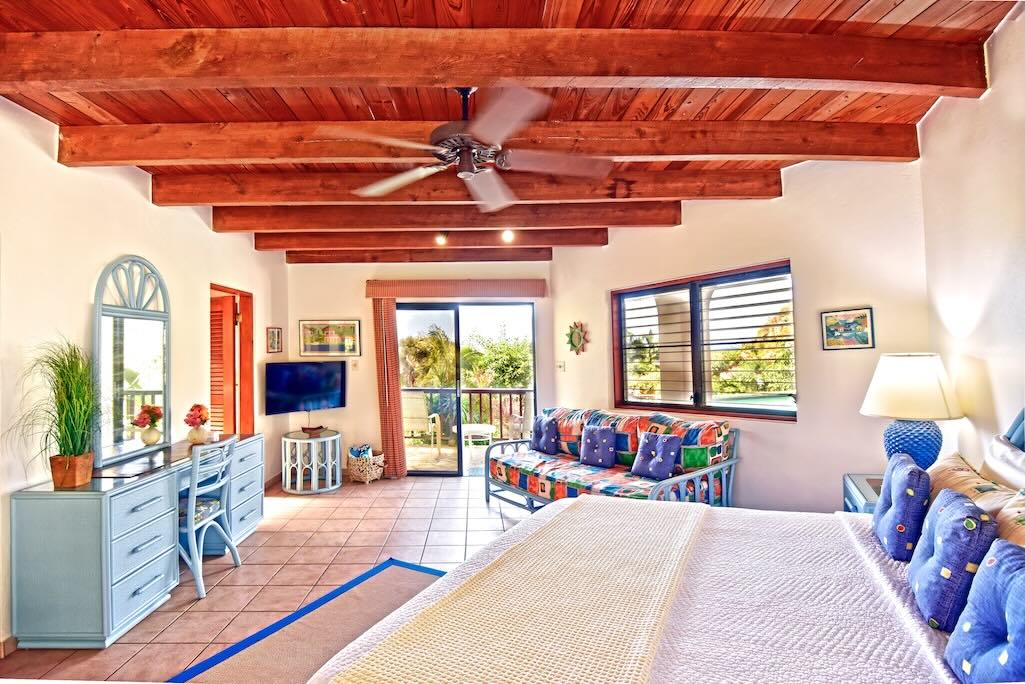 Loblolly Bedroom Beams Guest room at Loblolly Villa with a king bed, lofted, wood-beam ceiling, a desk and chair and a glass door to a patio.