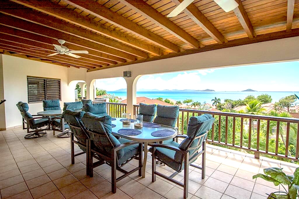 Loblolly_Patio Seating & View Loblolly Villa’s outdoor dining area on a covered porch with the sun shining on Mahoe Bay in the background.