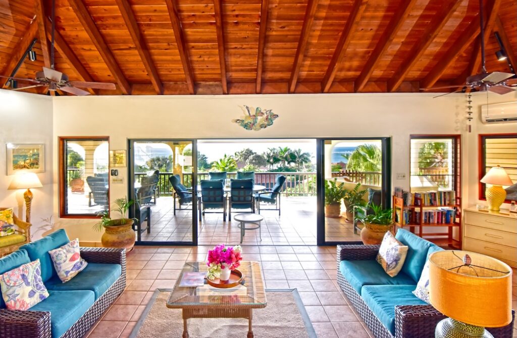 Loblolly_Living Room Loblolly living area with couches on either side of a coffee table, tile floors and an open glass door to a spacious patio with outdoor seating in the backgtround..