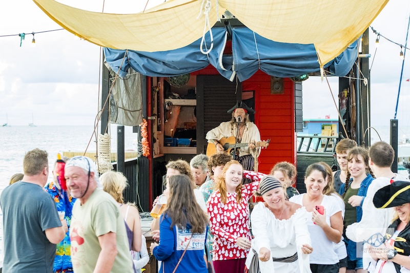 A pirate music show with Michael Bean performing on stage and a group of fmaily and friends dancing and enjoying themselves in the crowd. 