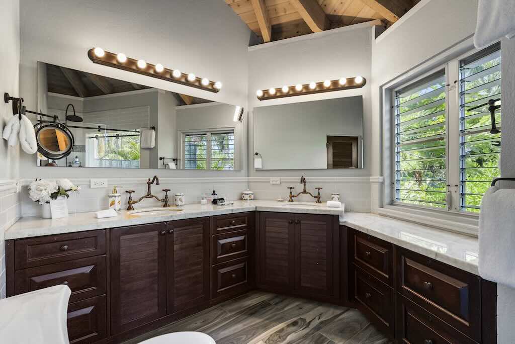 Sandcastle Villa_Bathroom Large master bathroom with wraparound white stone counters, dark cabinets and double sinks and vanity.