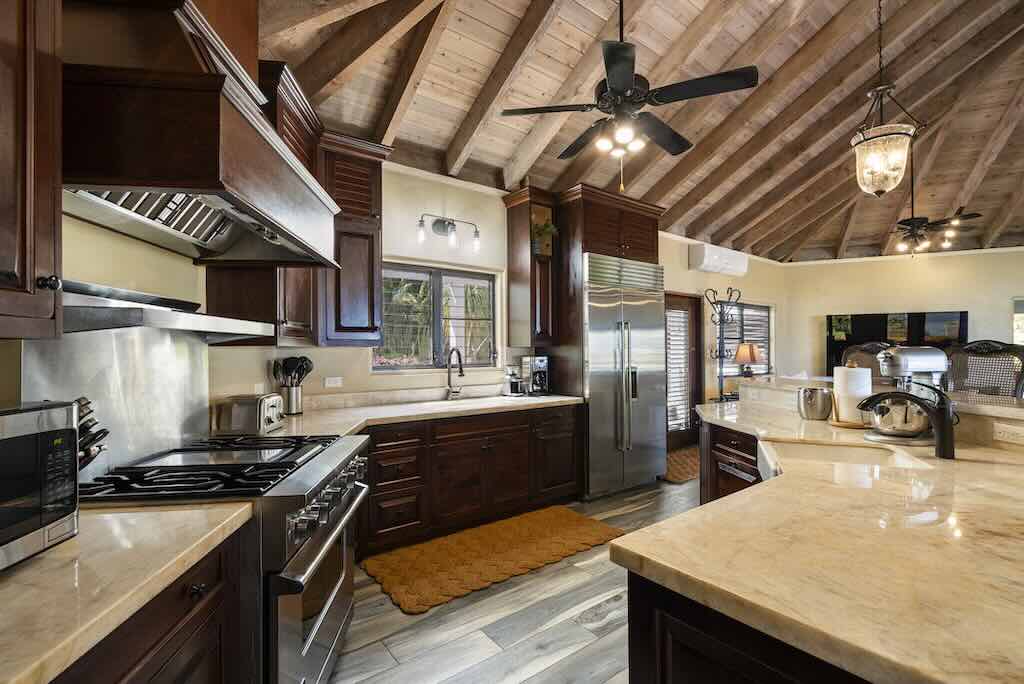 Sandcastle Villa_Kitchen Kitchen and island area with light granite counter tops, dark wood cabinets, and steel appliances in the bright and spacious main room.