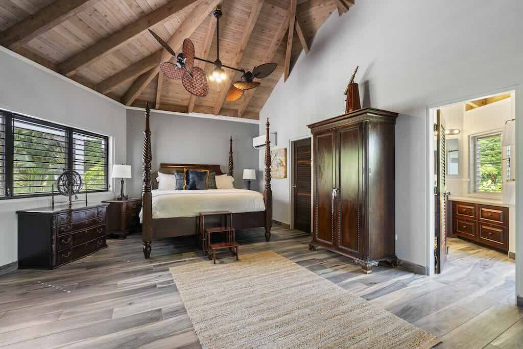 Sandcastle Villa_Master Suite Sandcastle's master suite with wood floors, a four-post bed, ceiling fans and the door open to the en suite bathroom.