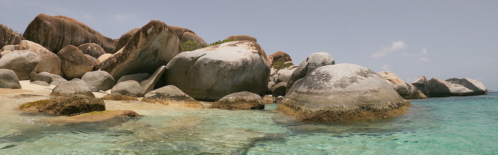 Beach with rock formations on the left against crystal clear blue waters at Devil's Bay Beach. 